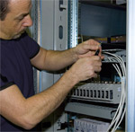 Technician wiring a equipment room with fibre optic cables